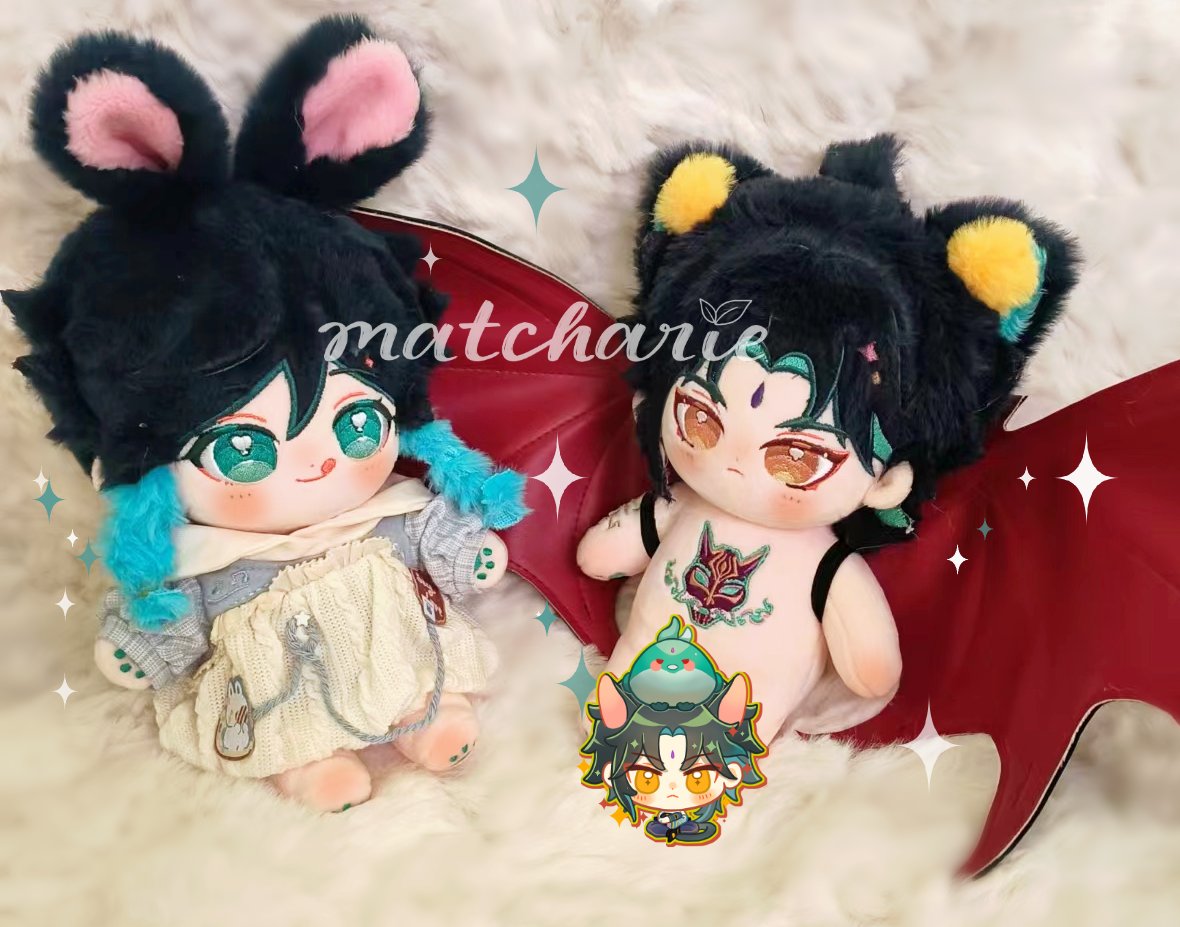 two anime character plushies with big eyes,  sitting on a fuzzy white surface. the plushie on the left is a rabbit with light pink ears and a light blue scarf. the plushie on the right is a demon with yellow ears and red wings. both plushies are adorable and soft. they look like they are made by hand.