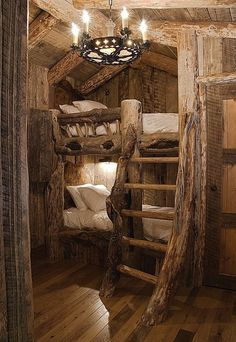 the image showcases a rustic bedroom interior featuring a uniquely designed bunk bed made primarily of wood and raw logs. the bunk bed is constructed to resemble natural tree trunks, incorporating branches and bark for a raw, outdoorsy feel. a wooden ladder with similar rustic construction leads to the top bunk. soft pillows and bedding are arranged on both bunks. a chandelier hangs from the ceiling providing ambient lighting. the surrounding walls and floor are also made of wood, completing the rustic aesthetic. a wooden door is visible to the right, suggesting a bedroom or cabin setting.