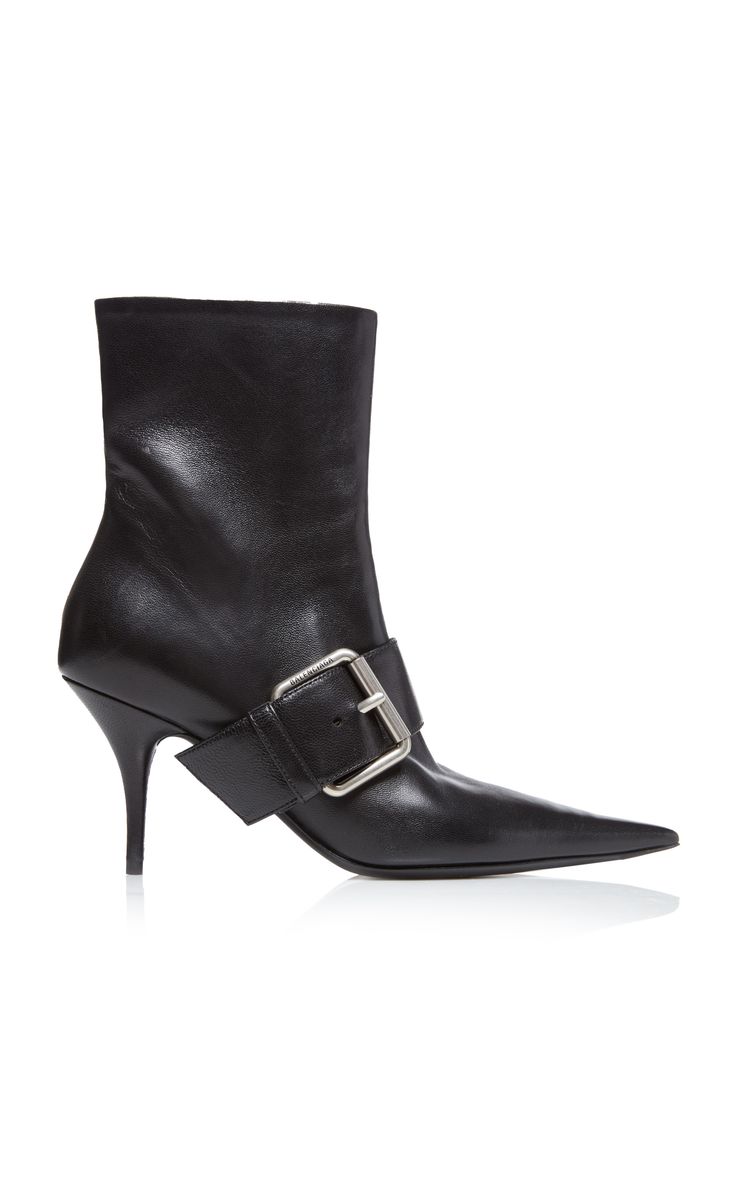 a studio shot of a pair of women's black leather ankle boots with a pointed toe, stiletto heel, and buckle detail. the boots are isolated on a white background.