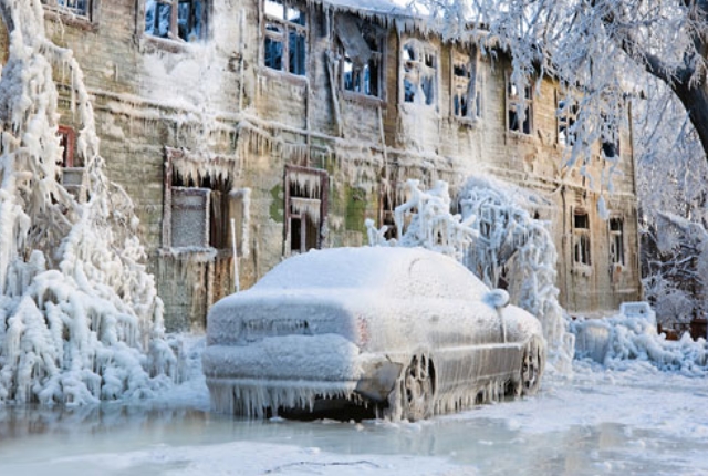 a car covered in ice sits in front of a house completely covered in ice. the entire scene is frozen over and covered in snow. the car is frozen solid and the house looks abandoned. the scene is a winter wonderland, but it is also a reminder of the power of nature and the dangers of winter.
