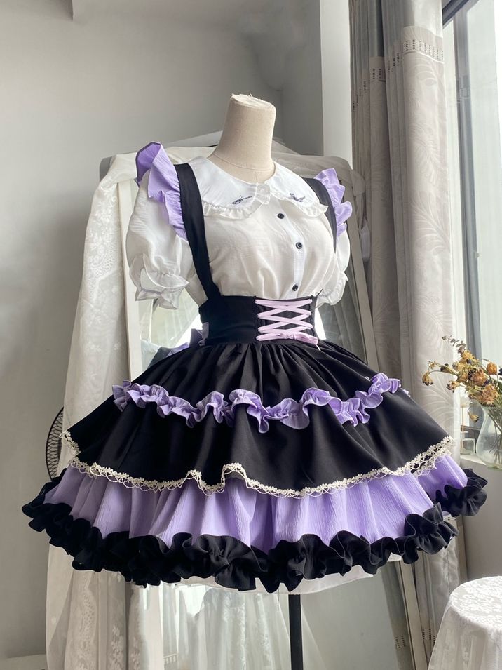 a purple and black lolita dress displayed on a mannequin. the dress features a white blouse with a peter pan collar and black buttons, a black bodice with a laceup back, and a tiered skirt with purple and black ruffles and lace trim. the dress is styled with a white petticoat to add volume. the mannequin is positioned in front of a white wall with a window to the right. the lighting is bright and artificial, typical of a studio setting.