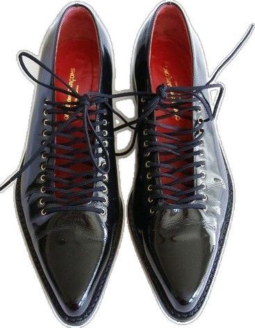 a pair of black, leather, pointed toe shoes with laces. the shoes have a red lining and are tied up. the background is white.
