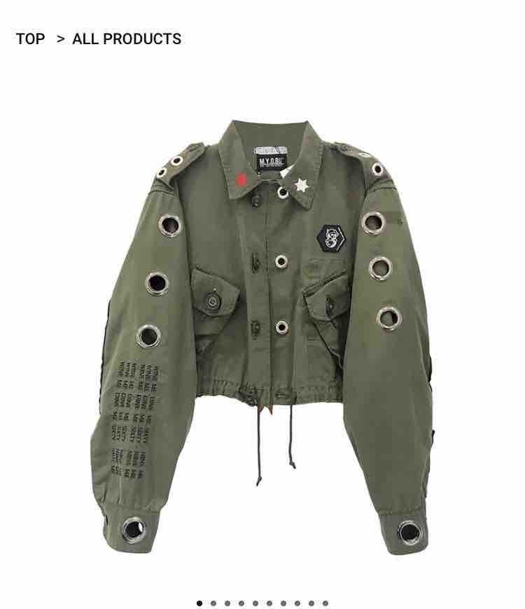 a cropped olive green military jacket with distressed details, ripped denim, and metal eyelets. it has a grunge and punk aesthetic, making it perfect for streetwear fashion.