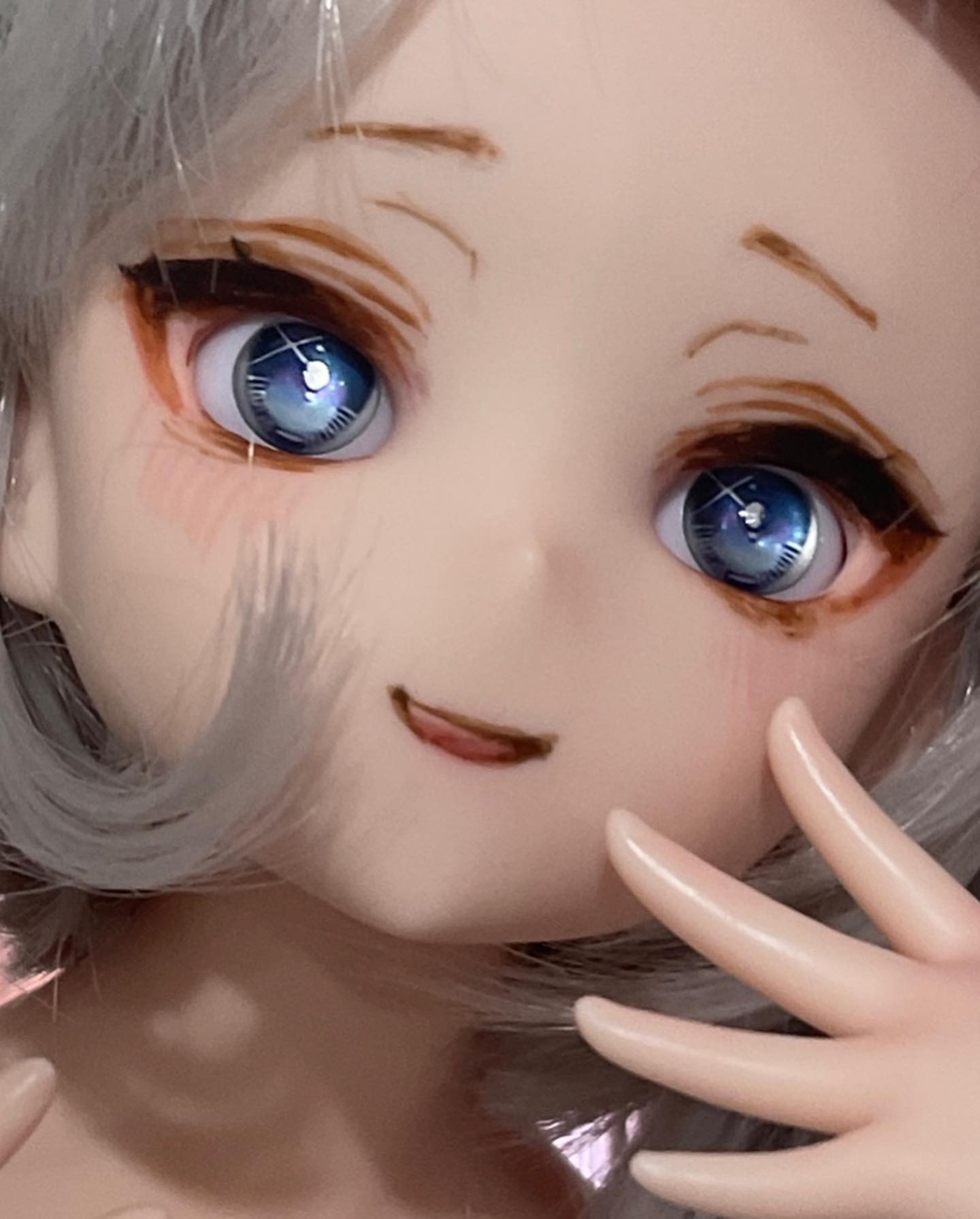a closeup portrait of an anime doll with white hair and blue eyes,  she is smiling with her fingers in the frame. the doll's skin is white and smooth, and her eyes are large and bright. her hair is styled in a simple way, with the bangs framing her face. she is wearing a white outfit. the doll's expression is sweet and innocent.  she is a popular anime character, and her image is often used on merchandise and in media.
