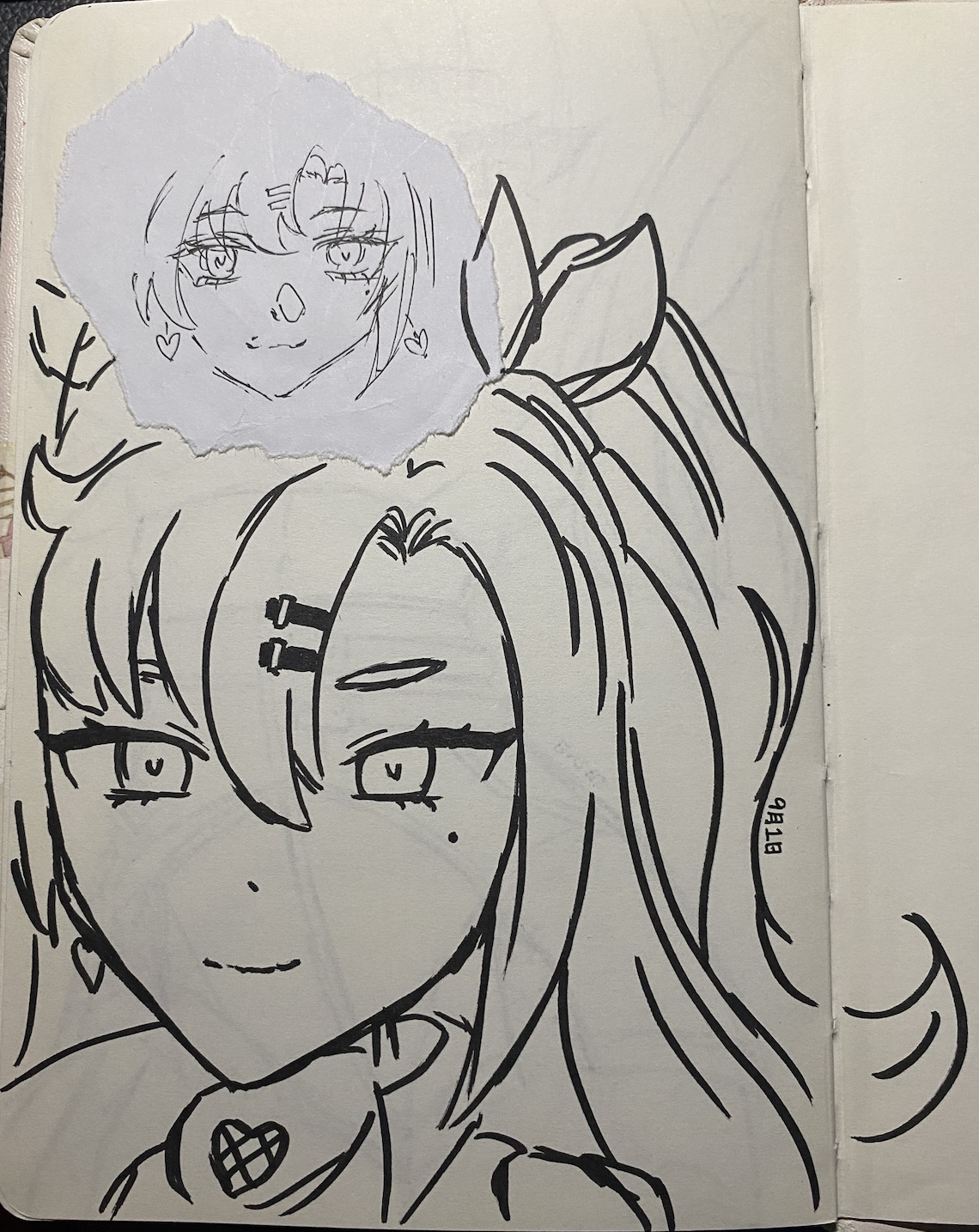 he image shows a closeup of a sketchbook page featuring a black ink drawing of an animestyle girl. the girl has long hair styled in a ponytail, and her face is drawn with large expressive eyes. on top of the drawing, a smaller, slightly crumpled piece of paper has been affixed. this smaller piece features a simpler sketch of a similar animestyle female face, possibly a preliminary version or a different character altogether. the style is consistent with typical anime/manga aesthetics.  the larger drawing incorporates some stylistic shading and linework. the sketchbook paper itself is visible around the drawing, and a small signature or marking is also visible. the overall impression is that of artwork in progress or a page from an art journal.