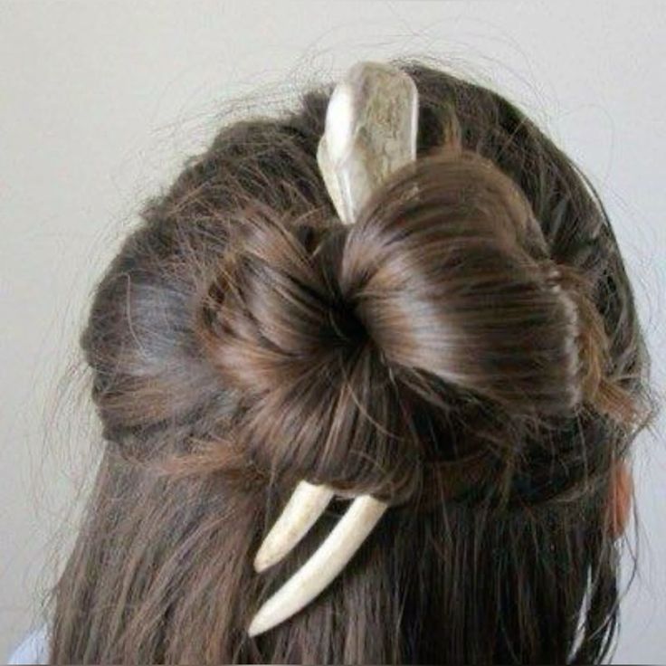 a woman with long brown hair has her hair up in a bun with a bone hair clip. the hair clip is white and has two prongs. the woman's hair is pulled back from her face and is styled in a sleek and elegant way. the hair clip is a beautiful accent to the woman's hair and is a stylish way to keep her hair out of her face.