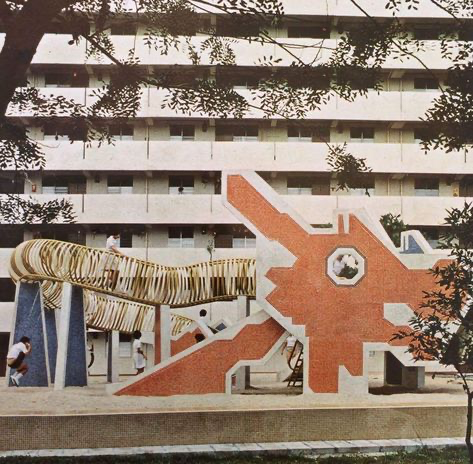 a modern, colorful playground made of concrete, built in front of an apartment building. the playground features a slide and jungle gym. there are people, possibly children, playing on the playground. the building is very modern and appears to be in a densely populated urban area.