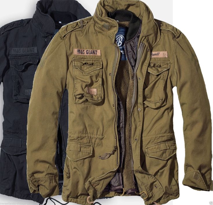 a closeup of a green, militarystyle jacket with a black zipper. the jacket is open and shows a brown fleece lining. the jacket has four flap pockets with button closures. the jacket has a black collar with a zipper closure and has two buttoned straps on the sleeves. the word "m65 giant" is seen on the left breast pocket in white lettering. the jacket is unbuttoned and shows the inside fleece lining which is brown. the background is white.