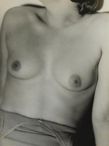 a black and white closeup photograph of a woman's torso, showcasing her breasts and upper abdomen.  the image is intimate and focuses on the texture and form of the body. the woman's skin appears soft and the lighting creates subtle shadows that accentuate the curves of her body. the overall tone is sensual and suggestive but maintains a degree of artistic abstraction.  she is partially clothed, wearing what seems to be the top of undergarments. the style of the photo suggests a vintage or classic photographic approach.