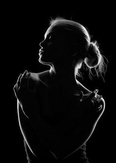 this captivating black and white photograph showcases the silhouette of a woman's upper body against a stark black backdrop. the image's beauty lies in its simplicity and the way light outlines the woman's form, highlighting her elegant pose and graceful curves.  her head is tilted back slightly, and her eyes are closed, creating an air of tranquility and serenity. the lighting is lowkey, with a rim light delicately tracing her edges, adding depth and dimension to the composition. the overall effect is both powerful and ethereal, celebrating the beauty of the female form in an artistic and evocative manner.