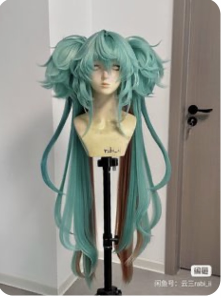 a tealgreen wig with long pigtails is displayed on a black mannequin head against a white wall. the wig features streaks of brown hair blended in.