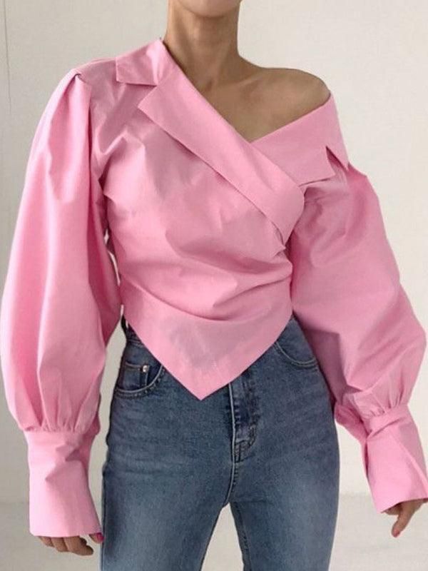 a woman is wearing a pink, longsleeved blouse with balloon sleeves and an offtheshoulder neckline, paired with blue jeans. the blouse has a wrap style and a pointed hem.