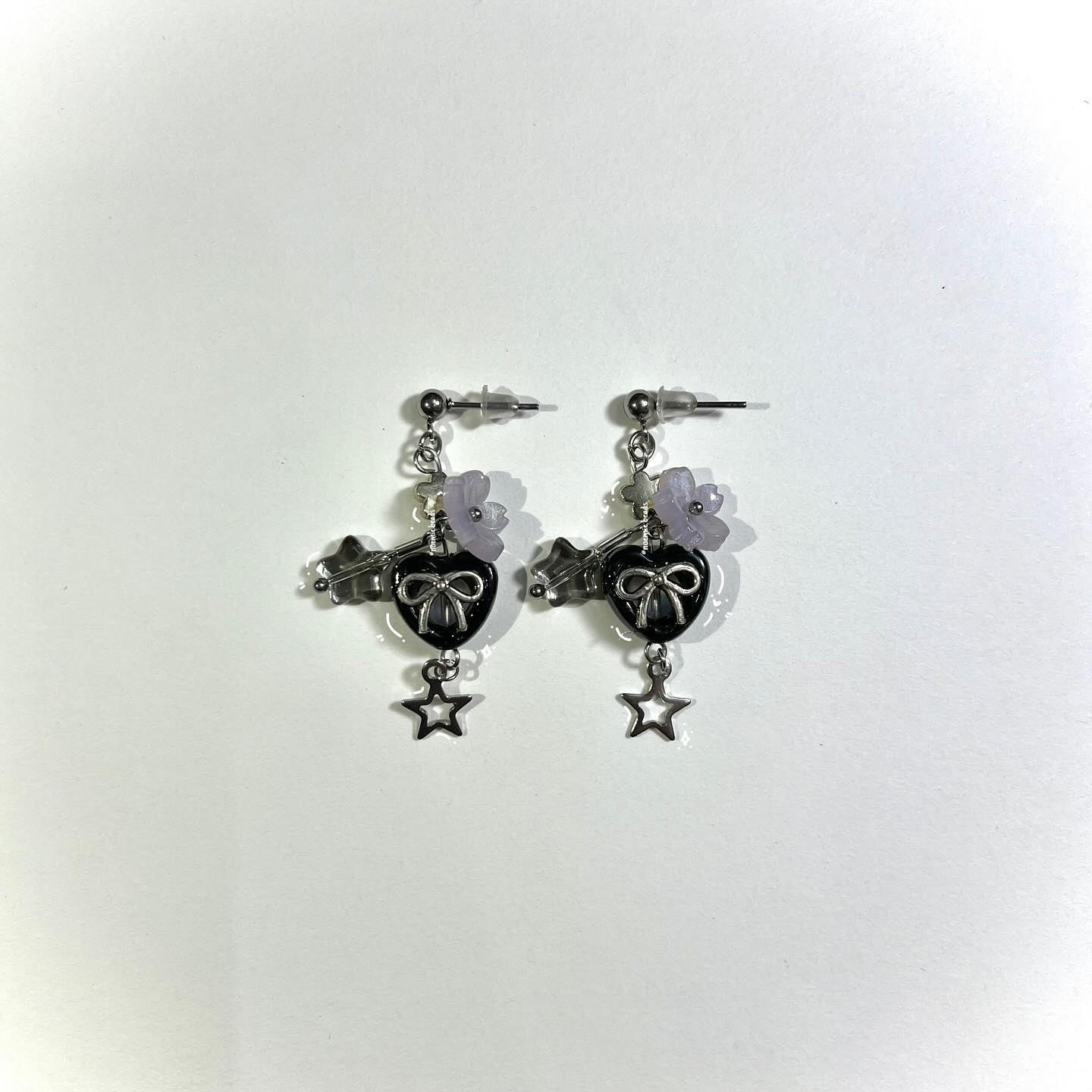 two earrings with a ball post at the top, connected to a flower, connected to a heart charm with a bow in the middle, connected to a star charm.