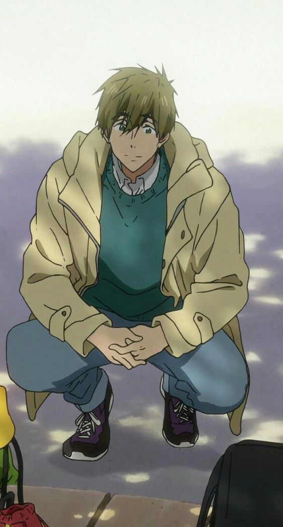 an anime boy with brown hair and green eyes wearing a beige jacket, teal sweater, blue jeans, and purple and gray shoes is crouching on the ground and smiling softly at something off screen.  there is a yellow and red object and a black object on either side of him, out of frame.  the background is white.