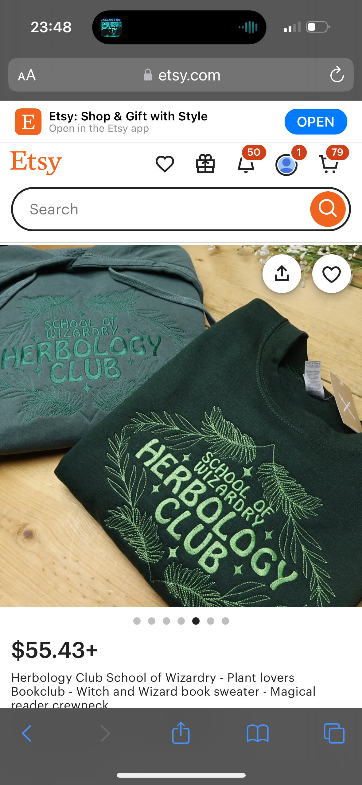 the image shows a green sweater with the words "herbology club" embroidered on it. the sweater is a crewneck and has the "school of wizardry" written above the words "herbology club". the sweater is laid out on a wooden table and looks like a comfortable and cozy piece of clothing.
