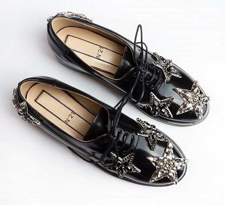 the image shows a pair of black n°21 women's oxfords. the shoes are patent leather and adorned with large, sparkling starshaped embellishments made of crystals or rhinestones on the toes and sides.  the shoes are laceup style and are photographed from above in a flat lay style against a white background. the brand's logo, "n°21," is visible inside each shoe. the focus is sharp, showcasing the detail of the embellishments and the quality of the shoes.