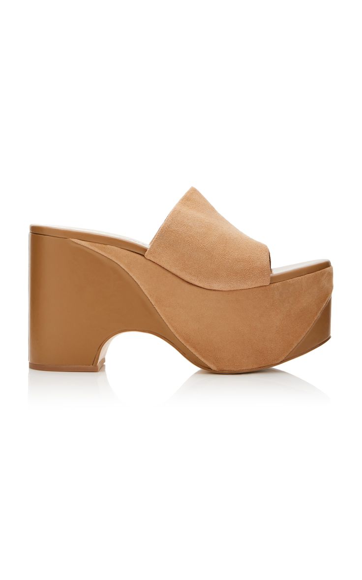 the image shows a pair of women's tan suede platform wedge sandals. the sandals are a light tan or beige color and have a slightly curved platform sole. the upper is made of suede material, and the sandals appear to be slipon style (mules). they are presented against a plain white background.