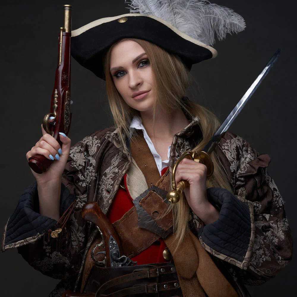 a young woman in a pirate costume is standing in a studio setting. she is wearing a black hat with a white feather, a brown leather jacket, a red shirt, and a black belt with gold buckles. she is holding a pistol in one hand and a sword in the other. she has a serious expression on her face, looking directly at the camera. the background is a dark, solid color. the image is dramatic and evocative, suggesting a sense of adventure and danger.