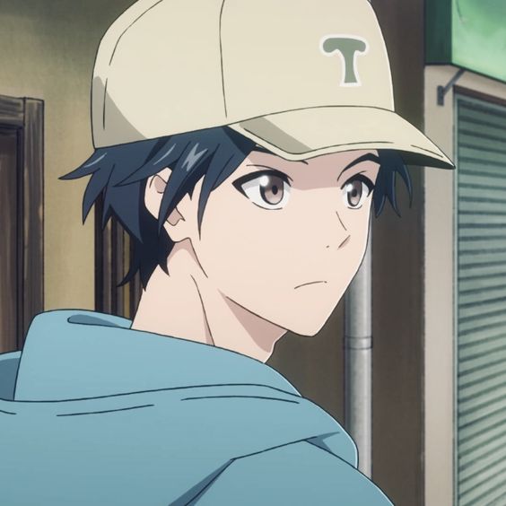 the image shows a closeup illustration of an anime boy standing on what appears to be a street corner. he is wearing a light blue hoodie and a beige baseball cap with a stylized "t" on it. his dark hair peeks out from under the cap, and his brown eyes gaze off to the side with a contemplative expression. the lighting is soft and natural, suggesting daytime. the overall tone of the image is calm and introspective.