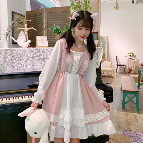 a young woman poses in a pink and white lolitastyle dress.  she is standing in a room with a piano and other furniture visible. the room is decorated in a cute and girly style. she is holding a white stuffed animal. the lighting is bright and natural.