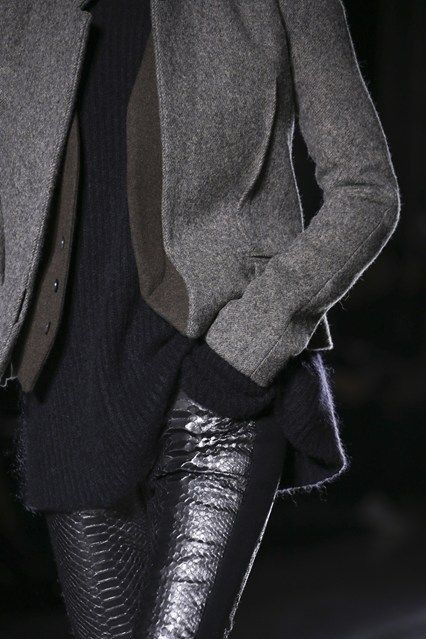 a woman wearing a grey jacket and snakeskin leggings stands and poses for the camera.