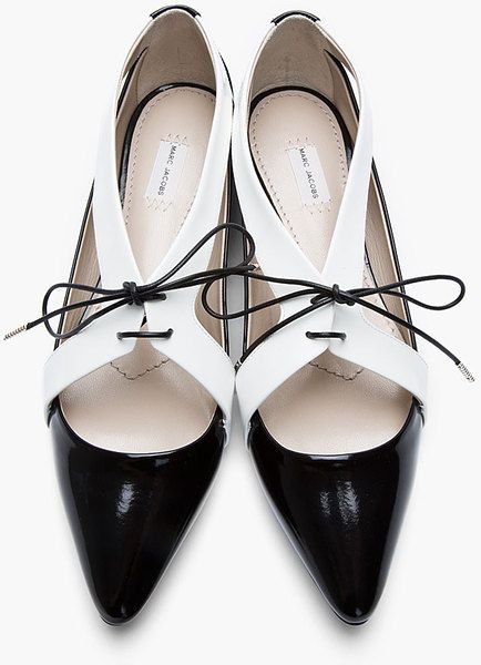 a pair of elegant black and white women's shoes by marc jacobs are shown.  they are pointedtoe d'orsay style shoes with a patent leather finish, featuring a black and white color block design and thin black laces. the shoes are angled slightly, showcasing their details.  the brand name "marc jacobs" is visible on the inner sole.