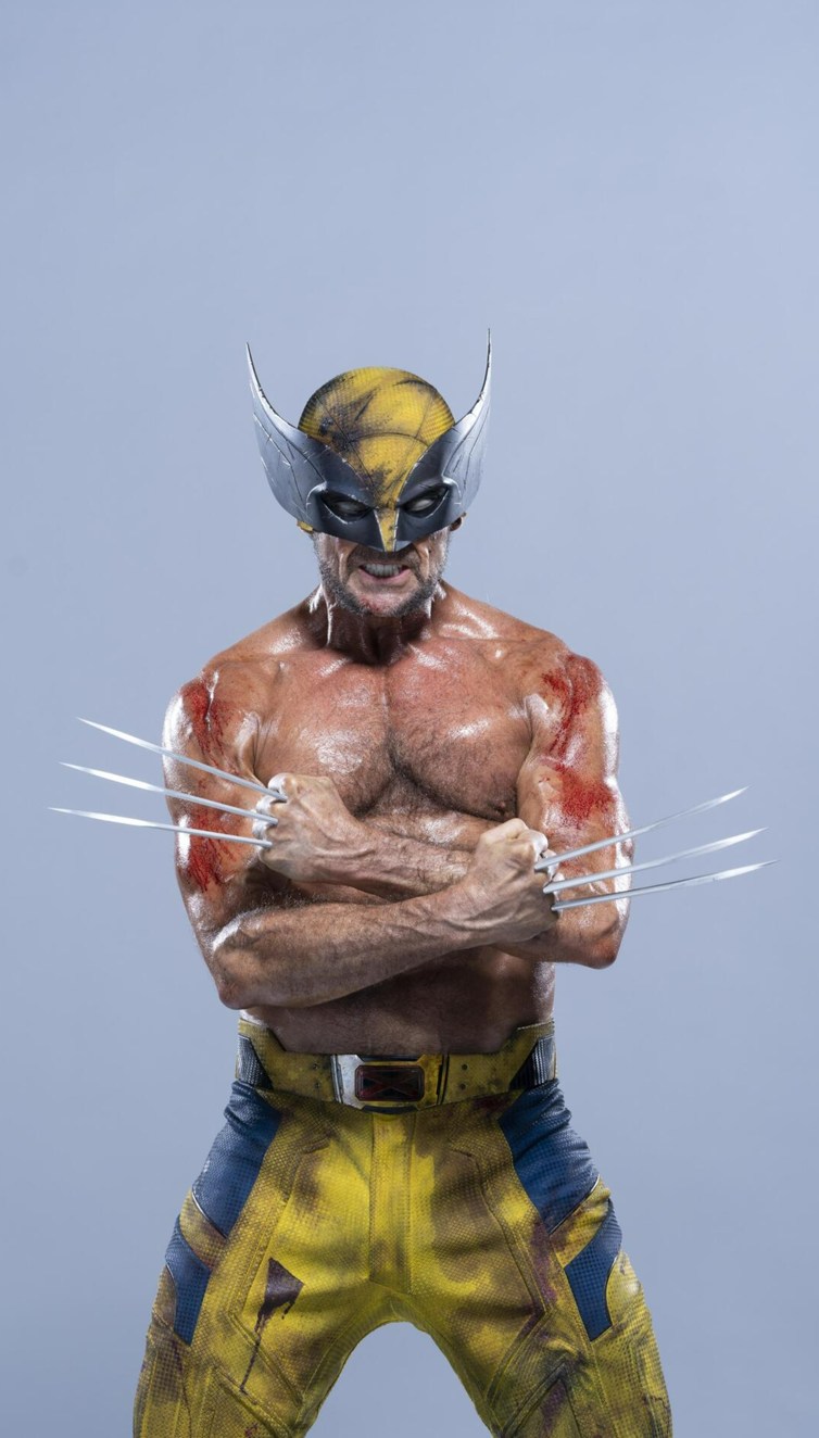a fullbody shot of a wolverine action figure. the figure is muscular and has metal claws extended from his knuckles. he is wearing a yellow and blue costume and a yellow and black mask with silver extensions on the sides. he has his arms crossed.