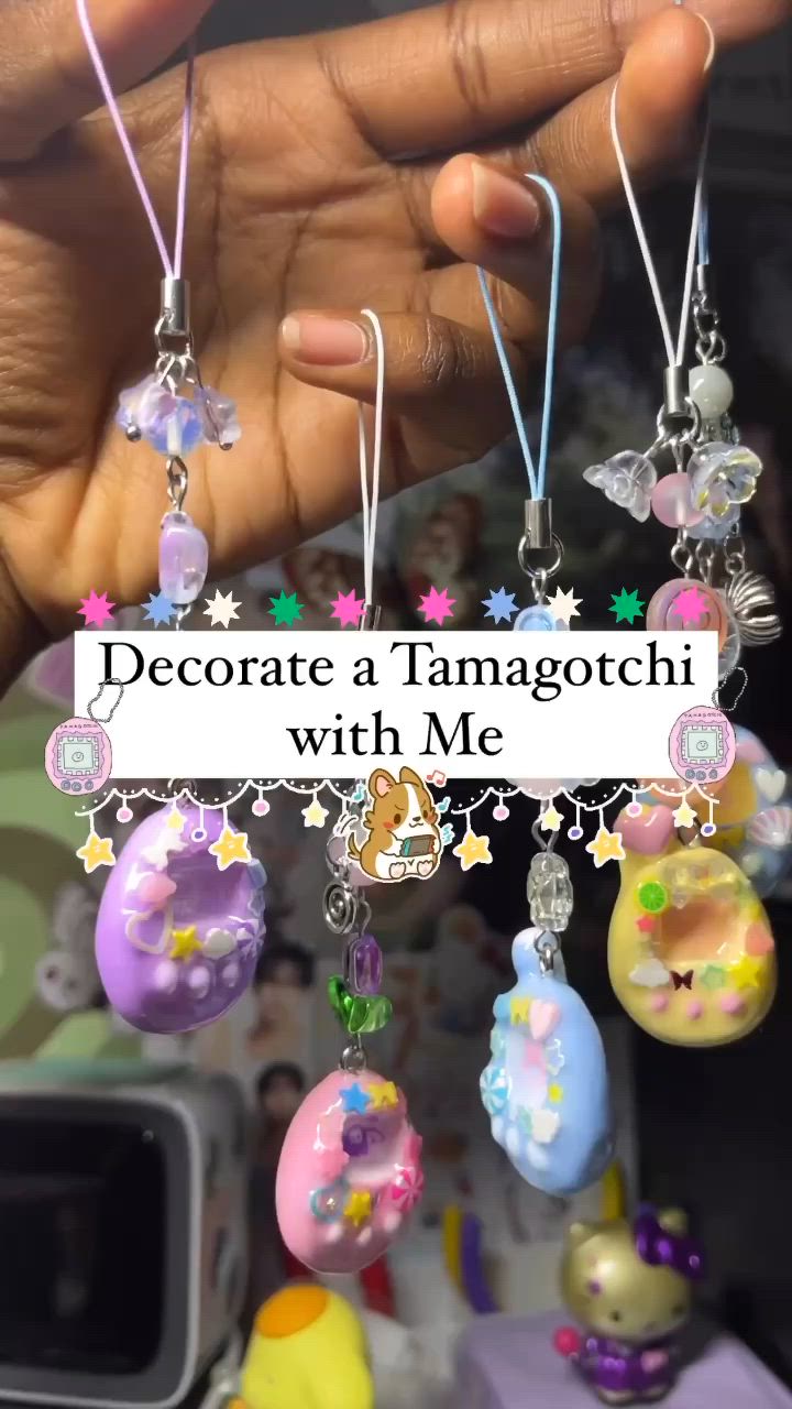 a hand is holding several tamagotchi charms with beaded straps and decorative elements like stars and flowers, with a text overlay that says "decorate a tamagotchi with me."