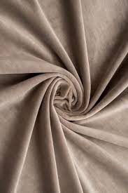this closeup image showcases a swathe of beige velvet fabric, its luxurious texture emphasized by the soft folds and gentle curves. the fabric appears smooth and inviting to the touch, its warm hue suggesting both comfort and sophistication. the tightly woven fibers create a subtle sheen that reflects light, adding depth and richness to the overall appearance.