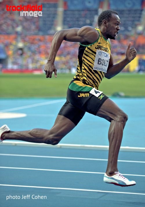 usain bolt, the renowned jamaican sprinter, is captured midstride as he races on a blue track during a track and field competition. his focused expression and powerful physique are evident as he pushes himself to the limit, demonstrating his incredible speed and athleticism. the blurred background suggests his rapid motion, while the stadium setting creates an atmosphere of highstakes competition. this image is a testament to bolt's iconic status in the world of sports.