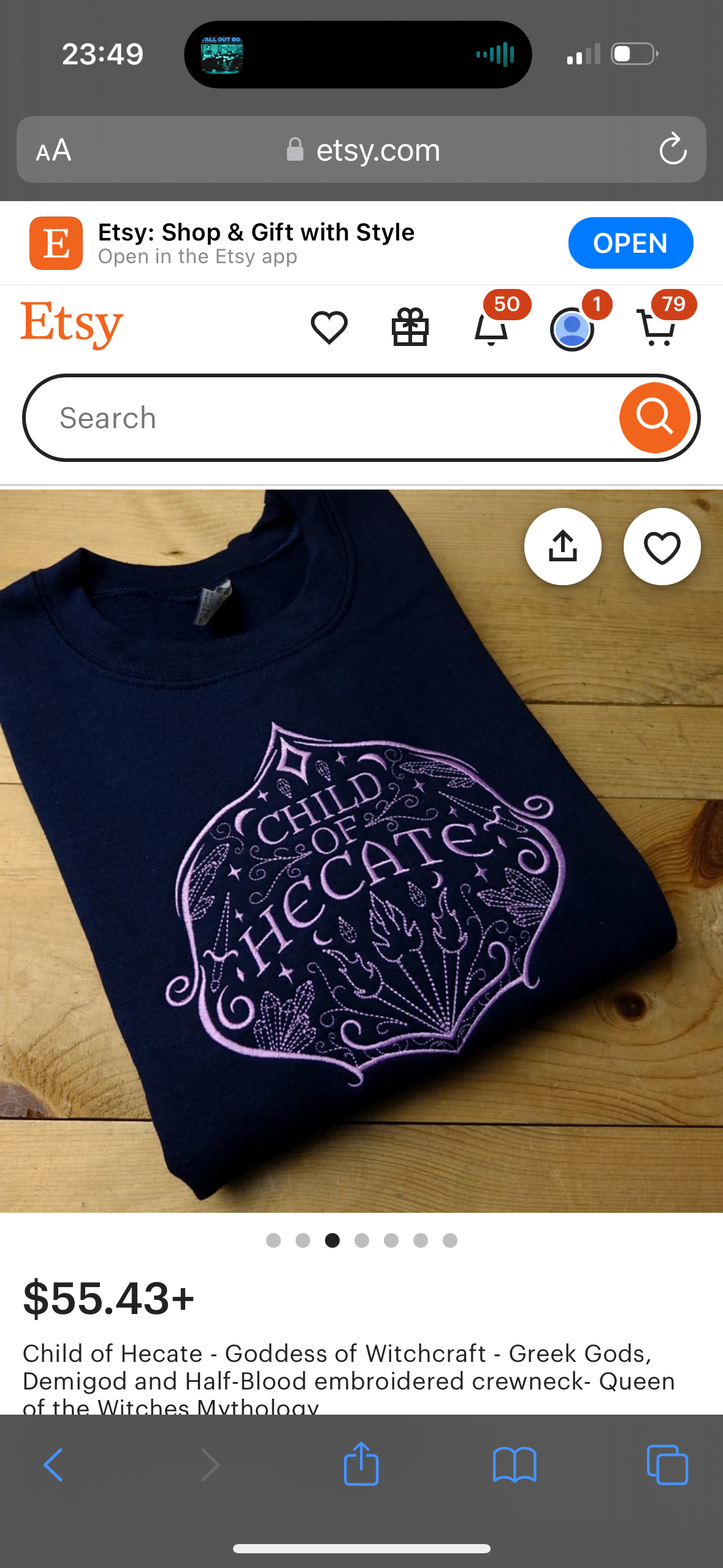 a blue crewneck sweatshirt with the words "child of hecate" in a purplepink cursive font that has been embroidered on the front of the shirt. the shirt is laid out on a wooden table with a white background. the shirt is for sale on etsy. the etsy app logo is in the top left corner of the image.