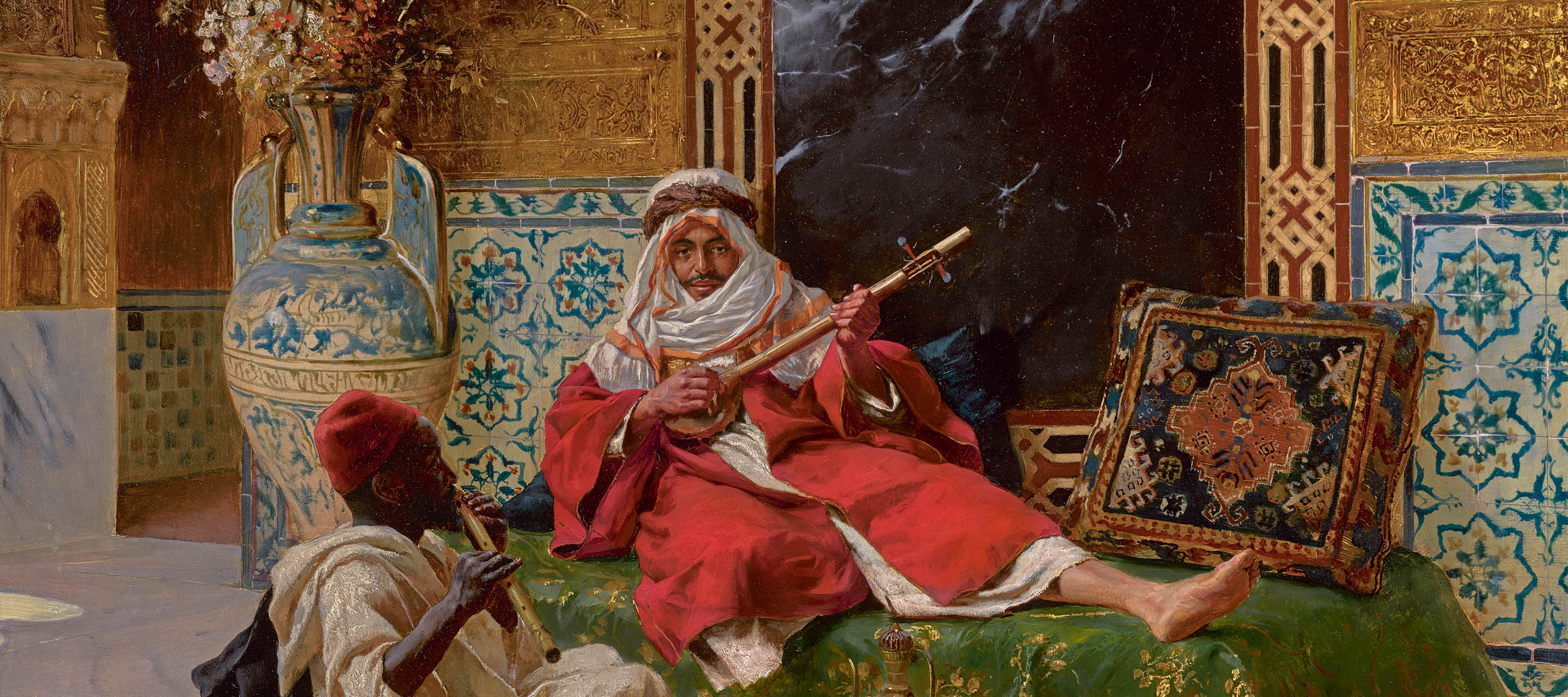 the image is a painting depicting two musicians in an opulent interior. one man, dressed in a white turban and red robe, is seated and lounging while playing a stringed instrument. another man, wearing a red fez and a white robe, is seated on the floor and playing a flute. the setting features intricate architectural details, including decorative tiles and ornate carvings. a large vase filled with flowers stands to the left, and a patterned cushion rests against the wall. the scene is rich in color and detail, characteristic of orientalist art.