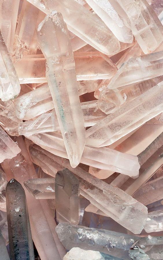 this is a closeup image of a pile of pink quartz crystals. the crystals are all different shapes and sizes, and they are scattered randomly throughout the image. the crystals are very shiny and sparkle in the light. the background is a blur of pink and white, which helps to highlight the crystals. the overall effect is one of beauty and tranquility.