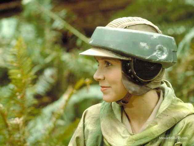 a closeup portrait of carrie fisher as princess leia organa in her camouflage gear with her iconic helmet on. the image is taken from star wars.