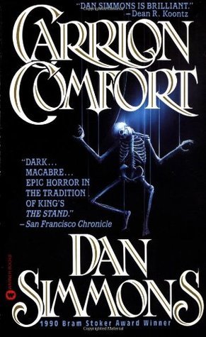 the image is a book cover for dan simmons' horror novel carrion comfort.  the cover features stylized lettering of the title "carrion comfort" in a serif font with gold accents against a dark background. a skeletal figure, appearing as a puppet, is centrally positioned, suggesting the macabre themes of the book.  quotes praising the book are visible, including one from dean r. koontz and a review from the san francisco chronicle. the author's name, "dan simmons," is prominently displayed below the title, along with the note that it won the 1990 bram stoker award. the overall design is dark and gothic, fitting the genre of the novel.