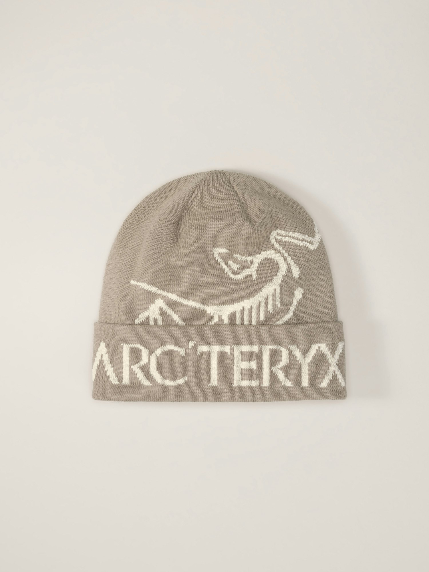 the image shows a closeup view of a grey arc'teryx beanie. the beanie is knit and features a creamcolored graphic of a mountain landscape and the arc'teryx logo prominently displayed around the lower cuff. the background is a plain, lightgrey, which ensures the beanie is the focus of the image. the overall presentation suggests a clean and minimalist aesthetic, typical of the arc'teryx brand.