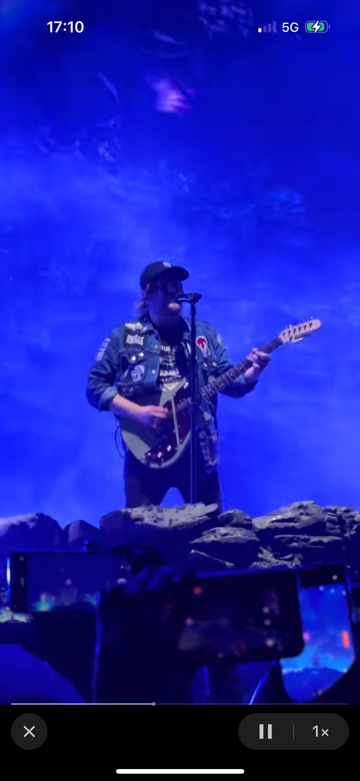 a musician with a guitar performs live on stage for a cheering crowd. the stage is lit by vibrant lights, creating a dynamic and exciting atmosphere. the musician, wearing a cool rocker style, engages with the audience as they enjoy the energy and passion of the performance. the image captures the essence of a live music concert, showcasing the power of music to connect and inspire.