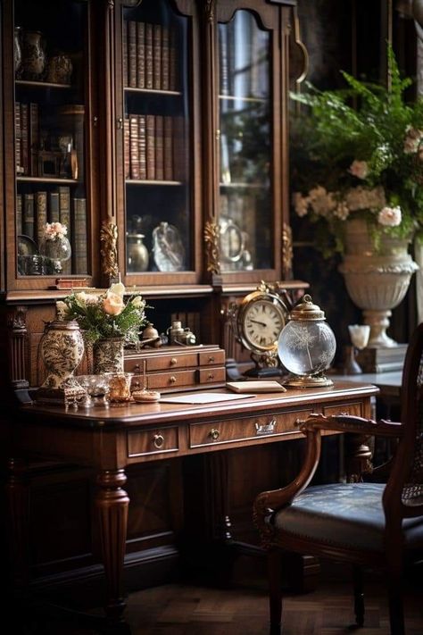 the image shows an antique wooden desk with a chair to the right. the desk has a glass dome on top of it. there is a gold clock to the left of the glass dome and a stack of books to the right. there is a vase of flowers on the desk, as well as a few other decorative items. behind the desk is a wooden bookcase with glass doors. the bookcase is filled with books and other objects. the room is dark and moody, with a vintage feel.