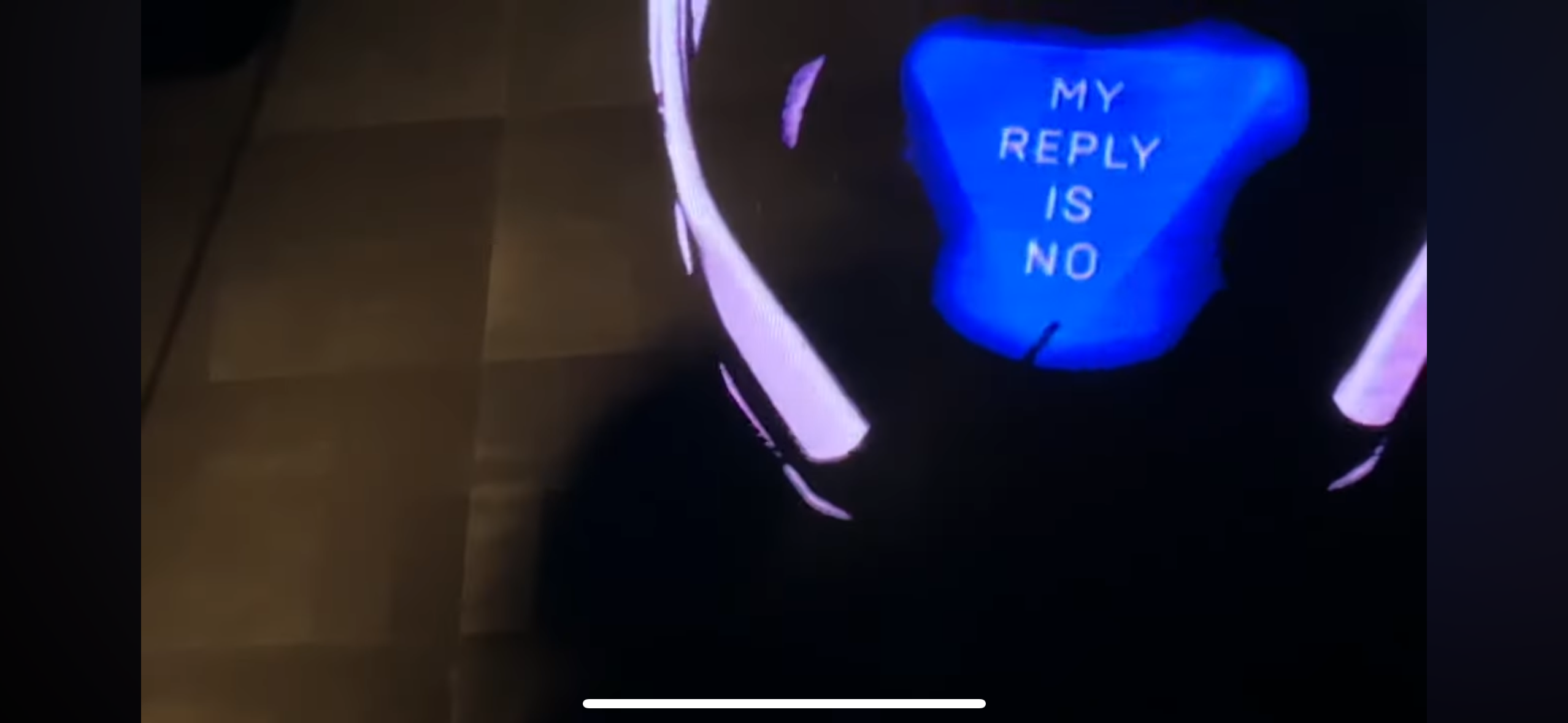 a closeup of a neon sign that glows purple and blue with the text "my reply is no." the sign is lit from behind and the glow is very bright, almost blinding.  the sign is sitting on a dark surface and there is some light reflecting off of the surface.