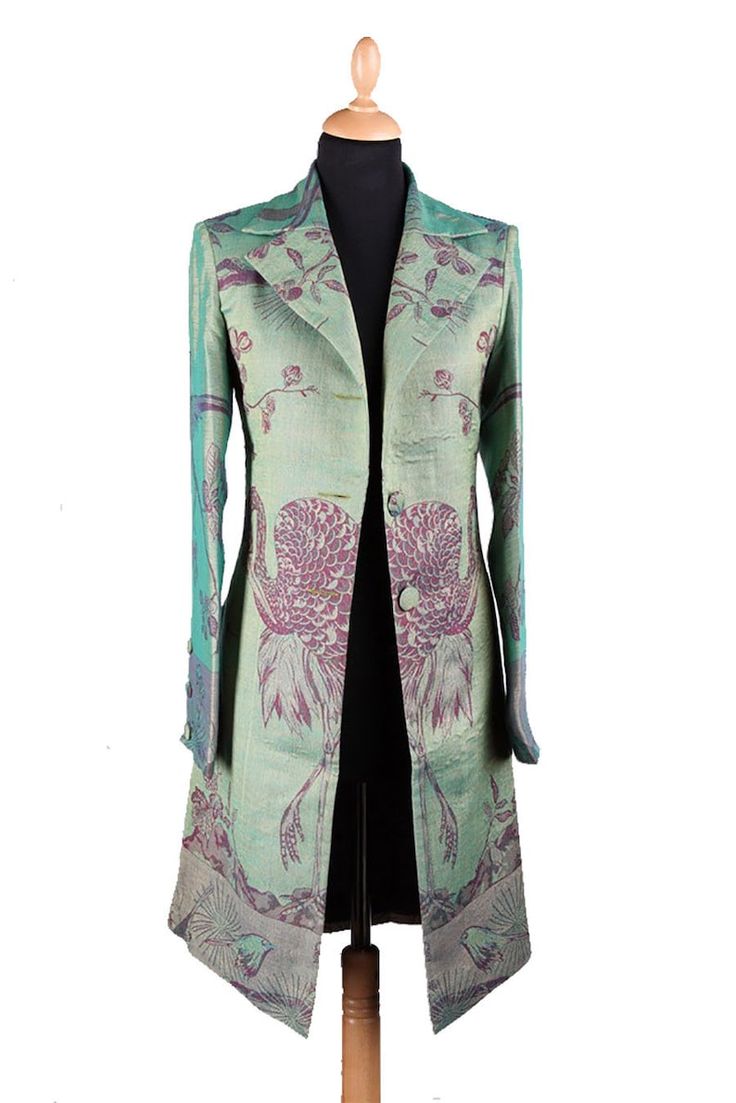 a green, longsleeved vintage jacket with peacock prints. the jacket has a button closure and is made from a fine, silky fabric.  it is a timeless and elegant piece of clothing.
