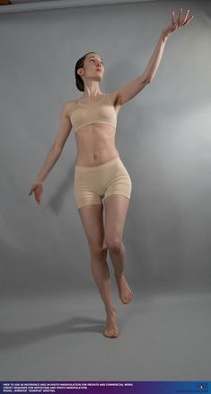 a woman with her hair pulled back in a bun is captured midpose against a plain gray background. she wears a pale, skintoned athletic bra and shorts, highlighting her lean physique. her body is arched back, her left leg lifting off the ground, and her right arm outstretched, as if reaching for something above and beyond her. the lighting is soft and even, emphasizing the contours of her body and the fluidity of her movement.