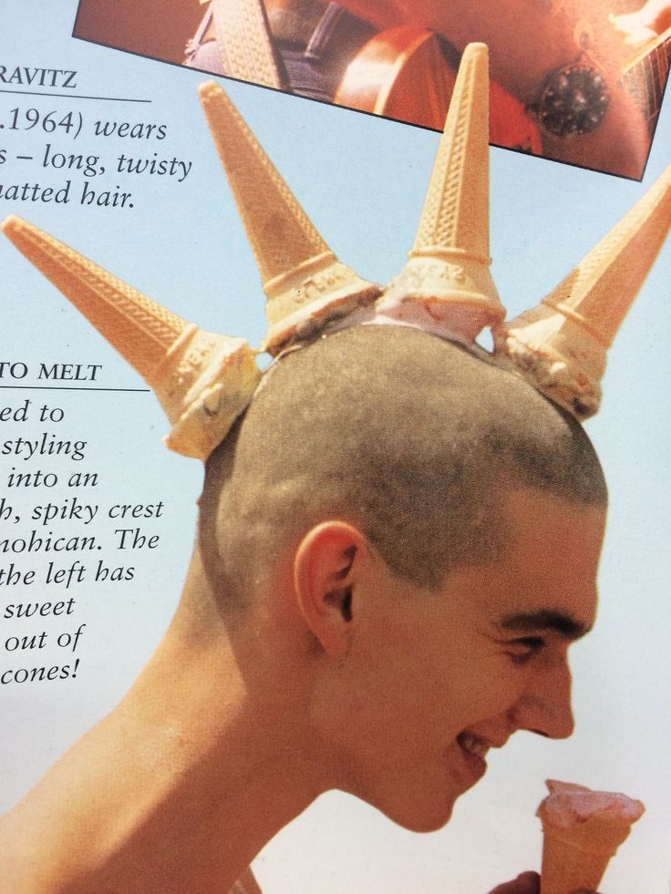a man, likely in his teens, smiles widely as he eats a chocolate ice cream cone with a mohawk style hair, his hair is made up of four ice cream cones.