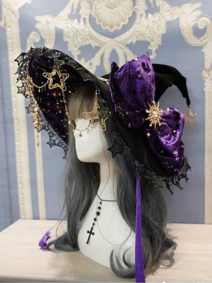 loseup shot of an elaborate witch hat displayed on a mannequin. the hat is black with a wide brim, adorned with purple velvet stars and a large purple velvet bow. gold star charms hang from the brim, and black lace accents the edges. the mannequin has gray hair and wears a simple black cross necklace. the background is a pale blue and purple damask pattern. the overall style is gothic lolita or dark academia with a whimsical and slightly spooky aesthetic.  the image is welllit and the details are clearly visible.