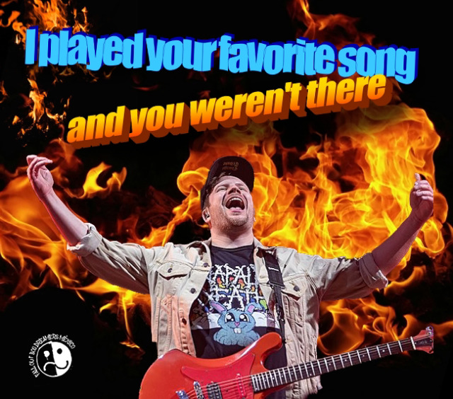 a musician is singing and playing a guitar on a stage in front of a crowd. he is surrounded by flames and his shirt has a band logo on it. the text "i played your favorite song and you weren't there" is overlaid on the image. this image is likely a meme expressing the frustration of performing for a small or nonexistent crowd.