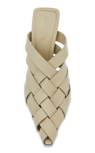 close up of a pair of women's woven leather sandals in beige. the sandals have a pointy toe and a braided design.