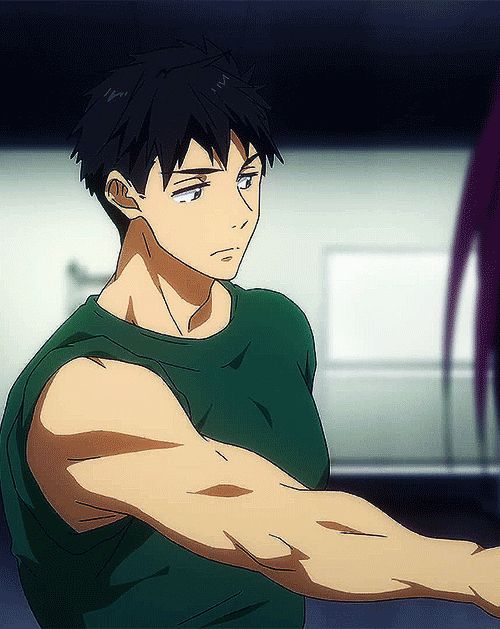 the image shows the side profile of a young, muscular man with short, dark hair and light skin. he is wearing a green tank top that reveals his toned arms and chest. the man appears to be indoors, and the lighting is artificial, casting shadows on his face and body. the image focuses on his physical strength and physique. he is turned slightly to the right with his arm extended, as if he is about to grab something.