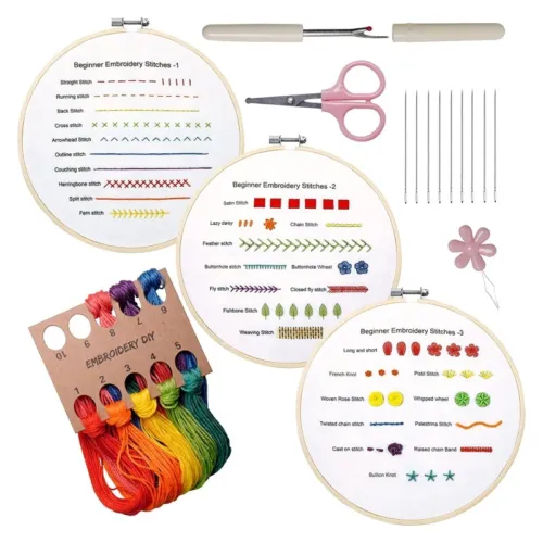 an embroidery starter kit containing three embroidery hoops with different beginner stitches patterns printed on them, a pack of rainbow colored threads, needles, scissors, a needle threader and a flower shape thread winder.