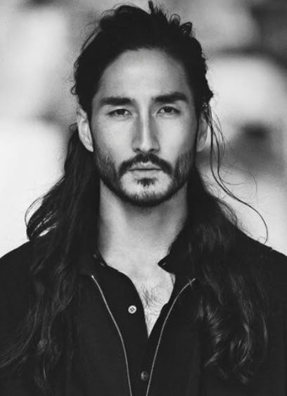 a black and white portrait of a man with long hair and a beard. he is wearing a buttondown shirt.