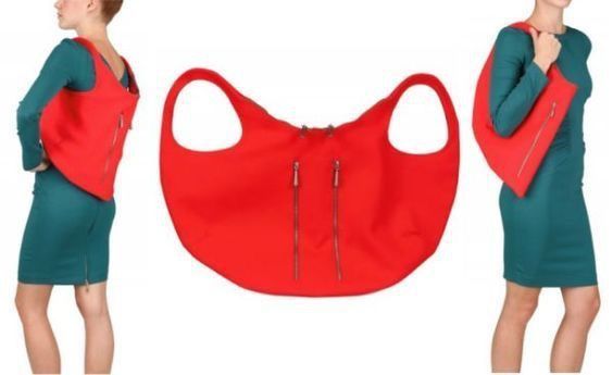the image shows a red bag displayed with two women wearing green dresses. the bag is displayed flat in the center, and worn by the women on the left and right. the bag has two zippers on the front, and the women are wearing it over their shoulder.