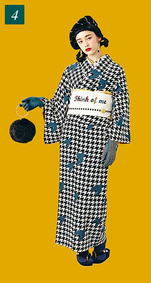 a fulllength shot features a woman in a stylish kimono and beret against a vibrant yellow backdrop. she is wearing a black and white houndstooth patterned kimono with blue birds scattered throughout. a white sash emblazoned with the phrase "think of me" cinches her waist. she accessorizes with blue gloves and carries a black, furlike purse. she also wears a black beret on her head.